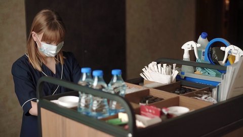 Housekeeper with protective mask at cleaning cart