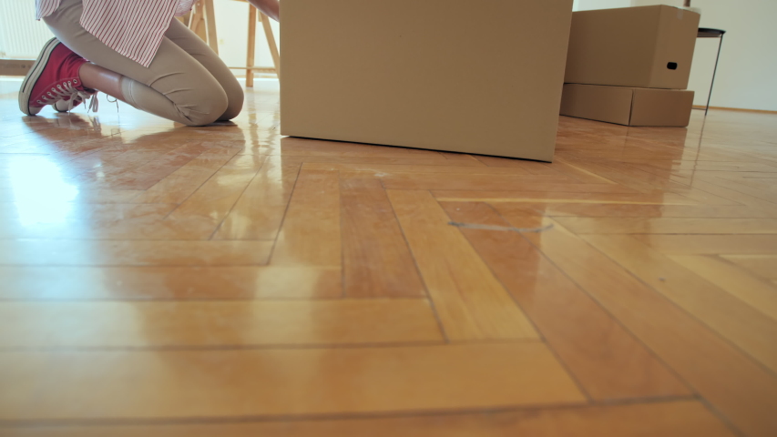 Young couple on a moving day. They are sitting on the floor in the living room and packing boxes