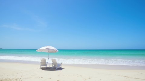 Mexico white sand beach and vibrant blue Pacific Ocean. Beach chairs and a parasol lie in the waves of the turquoise sea. Sunny vacation on the beach.