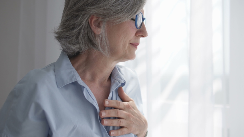 Adult woman holding hand on heart, feeling discomfort, risk of heart attack | Shutterstock HD Video #1055316290