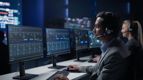 Team of Professional Traders Talking into Headsets Work on Computers with Screen Showing Finance Statistics, Charts Strategy, Stock, Telemarketing. Big Stock Firm Monitoring Room full of Specialists