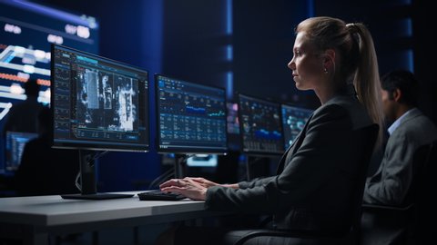 Female Cyber Security Agent Works on Personal Computer Showing Footage of Drone Surveillance Tracking of a Vehicle. Government Surveillance, Safety and Protection Program. System Control Room