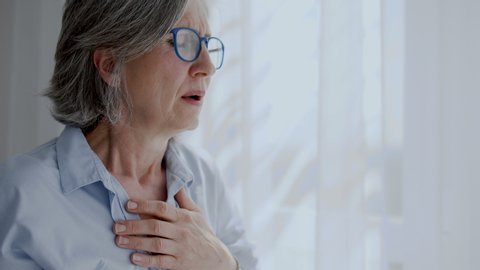 Mature woman hardly breathing and feeling pain in chest, heart attack, emergency