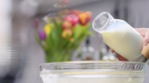 Milk is poured into a glass bowl. Process of making and whisking dough.