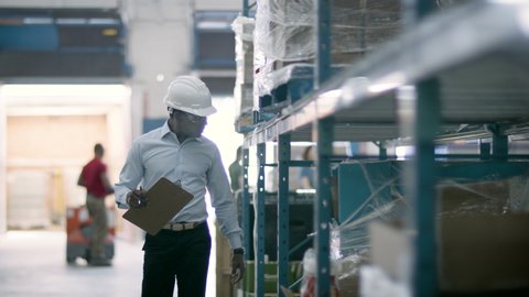 eCommerce warehouse manager inspects inventory at shipping centre. Business is booming online. Back to work. Shot in 4k.