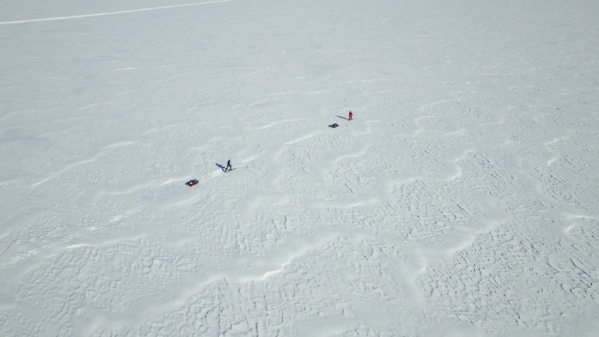 Two skiers are hiking towards South Pole, Antarctica and are pulling sleds. They are in the middle of nowhere on giant glaciers and icecaps facing snowy, icy mountain peaks