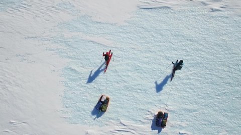 Two skiers are hiking over blue glacier and ice caps pulling sleds in Antarctica, South Pole