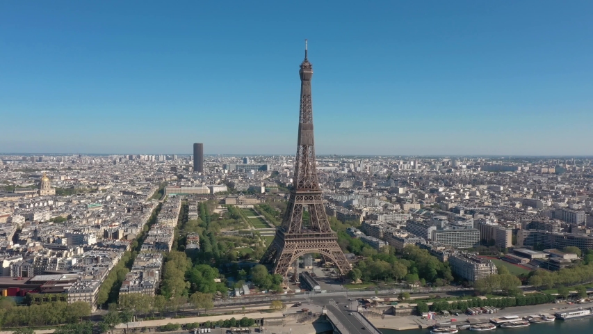 France, Paris Tour Eiffel (Eiffel Tower) in summer day, with Champs-de-Mars garden and Montparnasse tower. Long drone shot, aerial view above Seine river from left to right Royalty-Free Stock Footage #1055320727