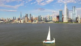 Aerial view of a sailboat going through the Hudson River.  A beautiful backdrop of New York City is in the backdrop