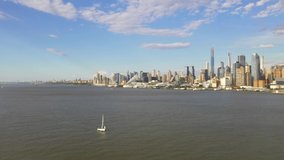 Aerial view of a sailboat going through the Hudson River.  A beautiful backdrop of New York City is in the backdrop