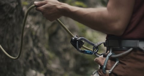 Climber protects rock climbing partner pulling a brake by hand on a belay rope outdoors lifestyle sport in nature unrecognizable slow motion close up