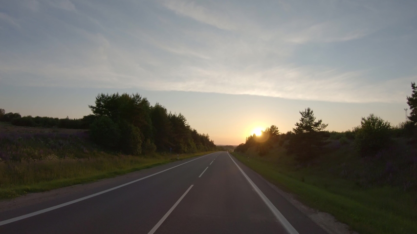 Driving along a rural road at sunset Royalty-Free Stock Footage #1055330405