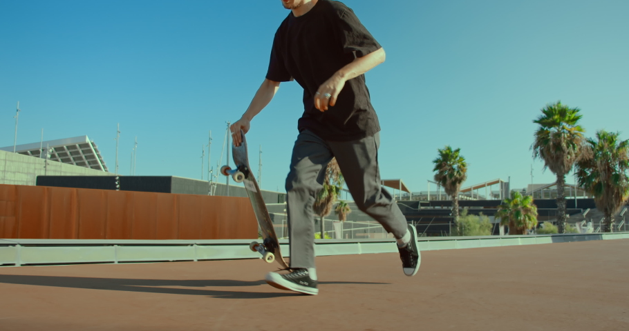 Young cool millennial man, teenager hipster in california rides his skateboard on boardwalk beach. Action wide shot of man perform skateboard tricks on sunny day in tourist spot | Shutterstock HD Video #1055331377