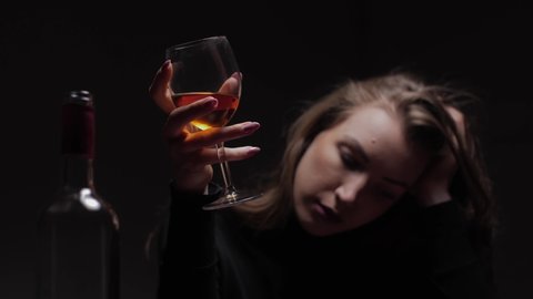 Young beautiful woman in severe depression, drinking alcohol. The concept of abuse and alcoholism. Alcoholic woman with bottle and glass of wine. 