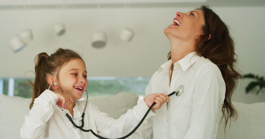 Authentic shot of a happy smiling little girl is playing doctor with her mother on a sofa in living room at home. Royalty-Free Stock Footage #1055336186