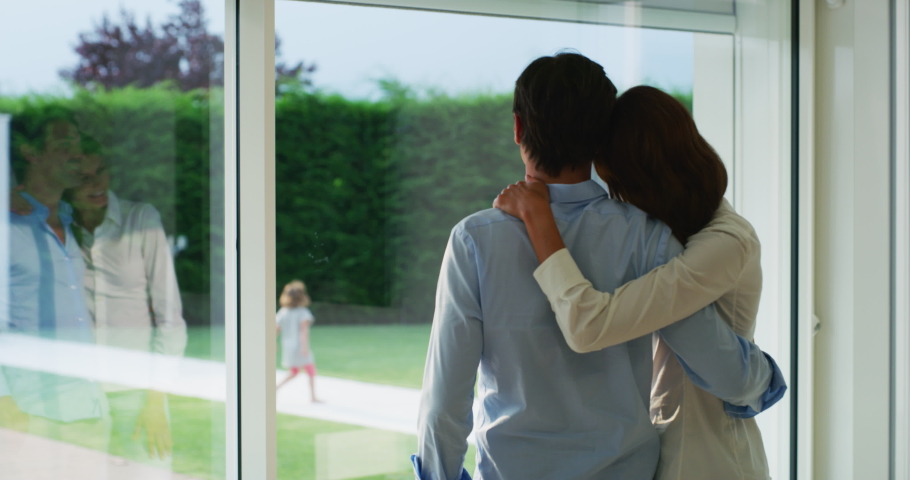 Authentic shot of lovely married couple is enjoying time together while looking through a window and watching their kids playing in a garden at home. Royalty-Free Stock Footage #1055336345