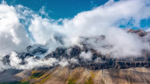 Rotation of teal blue lake with low clouds of rocky cliff face in Canada, Bow Lake Massive Rock Face Time Lapse Canadian Rockies Rotation Time Lapse 4K