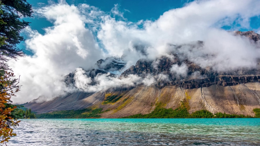 Rotation of teal blue lake with low clouds of rocky cliff face in Canada, Bow Lake Rotation Banff Jasper Time Lapse 4K Royalty-Free Stock Footage #1055336816
