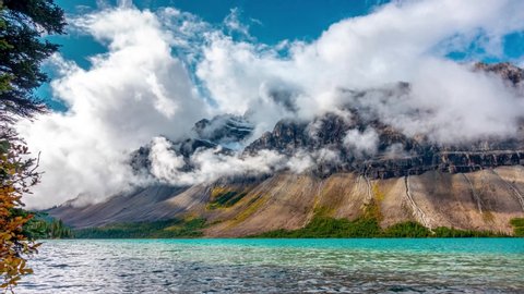 Rotation of teal blue lake with low clouds of rocky cliff face in Canada, Bow Lake Rotation Banff Jasper Time Lapse 4K
