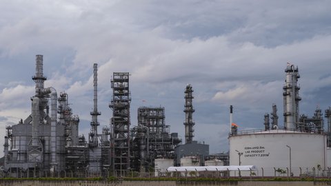 Time lapse of oil refinery plant chemical factory and power plant with many storage tanks and pipelines at sunset.