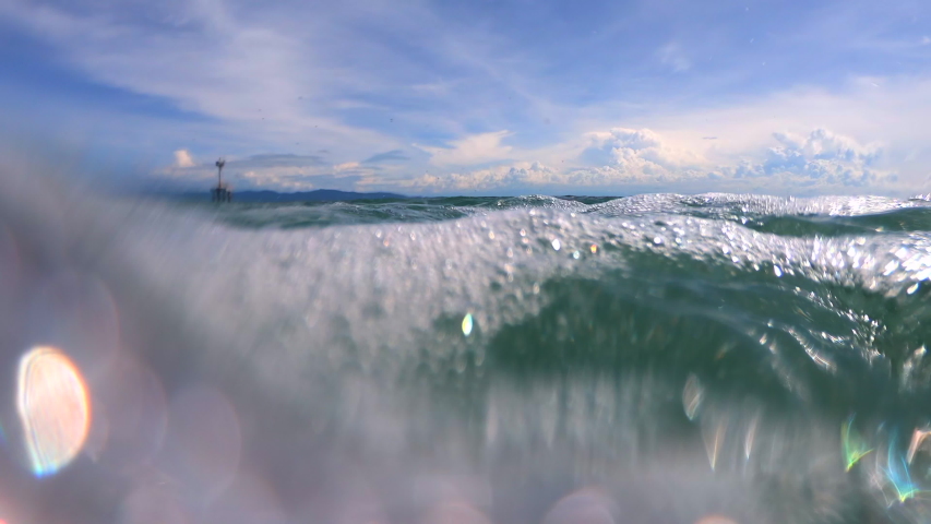Wave on moving water surface closeup in the middle of the screen.  Reach Back to the Water Surface in the middle of the sea