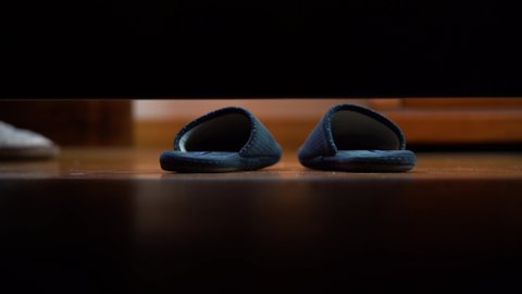 4k, Slippers on the floor.Man's foot put on slippers on the floor and go out. Camera  under the bed. View from under the bed.