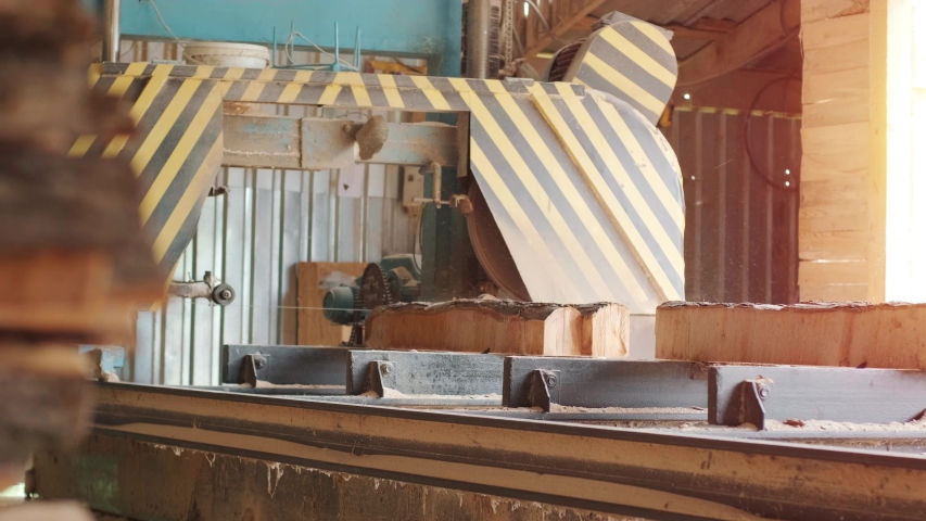 Sawing machine at wood production factory. Timber material processing and cutting at sawmill. Manufacturing process at lumber mill. Sawing woods on power machine. CNC machine