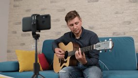 Young man is recording a guitar song to their online blog or Online guitar courses. Distance learning concept