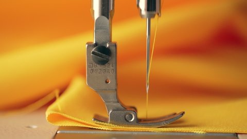 Sewing machine stitching of yellow clothes close up, macro. Slow motion frame of thread and needle. Textile fabric. slow motion 120 fps