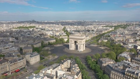 France, Paris Arc de Triomphe (Triumphal Arch) in Champs Elysees with Sacré-Coeur Basilica church in the background. Summer day. Aerial view from right to left (looks like helicopter or drone shot).
