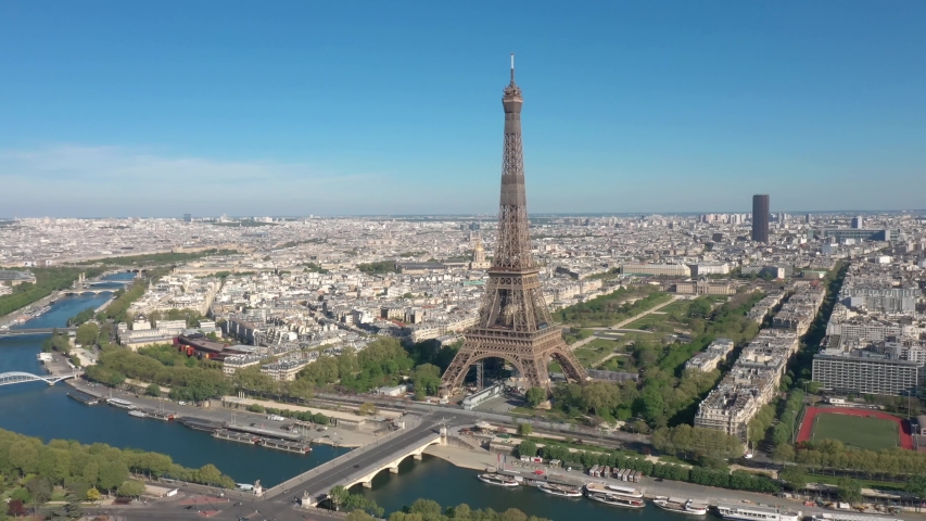 France, Paris Tour Eiffel (Eiffel tower) in beautiful summer day with blue sky. Montparnasse tower in the background. 4k quality drone shot, backward aerial view Royalty-Free Stock Footage #1055357132