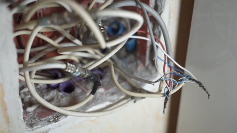 Electrical cables at home, white electrical wires in junction box inside the wall of residential building apartment. Twisted high voltage cables insulation, professional remodeling of open wires at