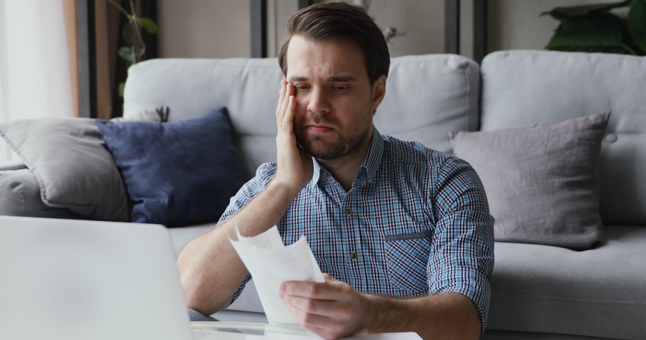 Man sitting in living room do finance analysis holds sales slip heap of receipt feels frustrated worried due lack of money, small business entrepreneur bankruptcy financial problems, overspend concept | Shutterstock HD Video #1055363192