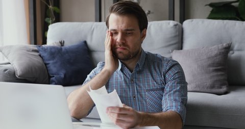 Man sitting in living room do finance analysis holds sales slip heap of receipt feels frustrated worried due lack of money, small business entrepreneur bankruptcy financial problems, overspend concept