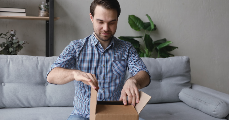 Man sitting on couch unpack received delivered parcel small box feels mad and frustrated due fragile goods broken, wrong order, bad condition or low-quality dissatisfied online purchase client concept Royalty-Free Stock Footage #1055363246