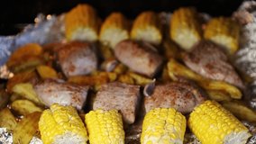 Delicious food baked in oven on foil.Natural pork meat steak cooked in stove with potatoes,rosemary spice & yellow corn.Tasty beef prepared at home for family dinner.Close up shot of supper meal