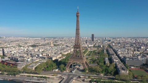 France, Paris Tour Eiffel (Eiffel Tower) in summer day, with Champs-de-Mars garden and Montparnasse tower. Long drone shot, aerial view above Seine river from right to left