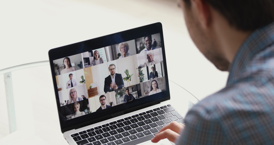 Concept of distant communication using laptop and internet connection, video call conferencing application. Diverse people young and old take part at group videocall activity, view over male shoulder Royalty-Free Stock Footage #1055370323