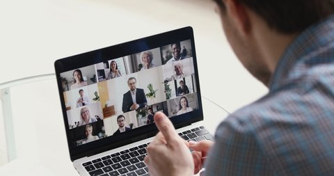 Concept of distant communication using laptop and internet connection, video call conferencing application. Diverse people young and old take part at group videocall activity, view over male shoulder