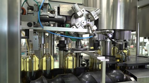 Wine production factory. Glass bottles filled up with white wine
Bottling production line.