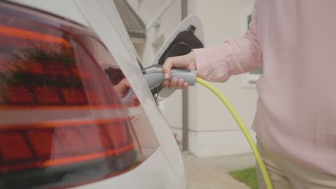 A woman charging her eco-friendly electric car at home