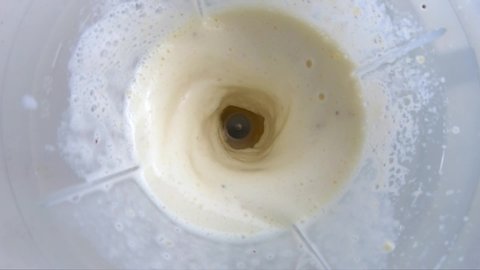 Banana smoothie with milk, beat in a blender. Top view and slow motion.