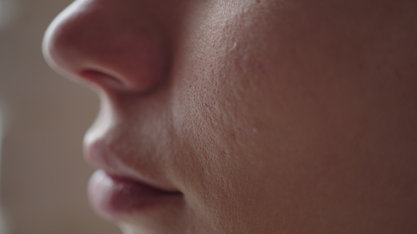 Close-up of a woman's cheek with a tear sliding down it. A tear slowly descends on the distressed face of a young girl, macro Royalty-Free Stock Footage #1055375570