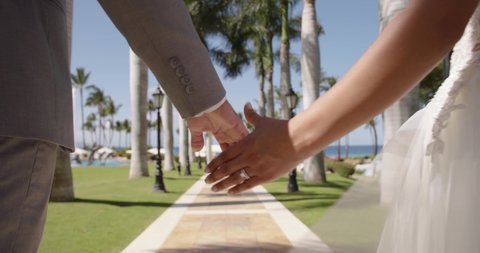 Married couple hold hands in tropical resort slow motion