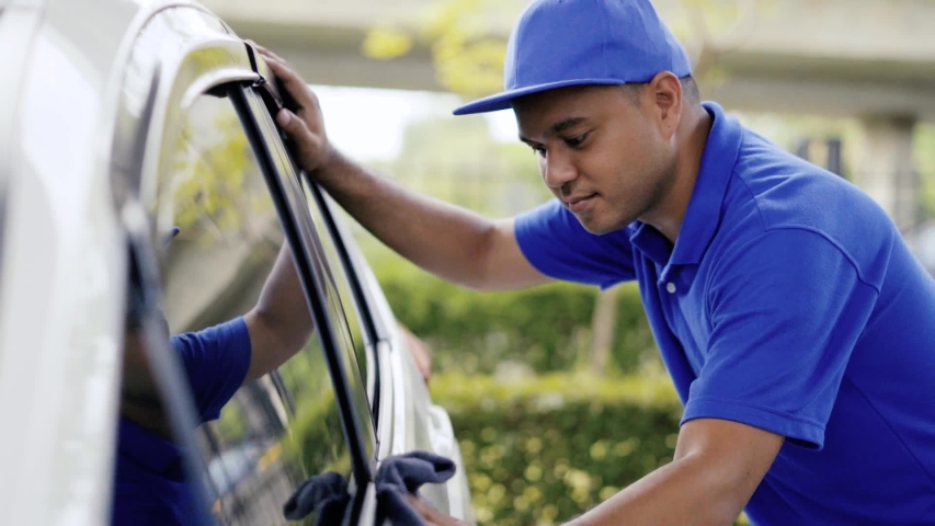 Offsite car cleaning staff provide excellent service. He is wiping the glass and the body of the white car. Worker washing car in the outside. Royalty-Free Stock Footage #1055378081