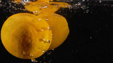 Many Slow Motion Fresh Orange Oranges Splash in Water with Bubbles
