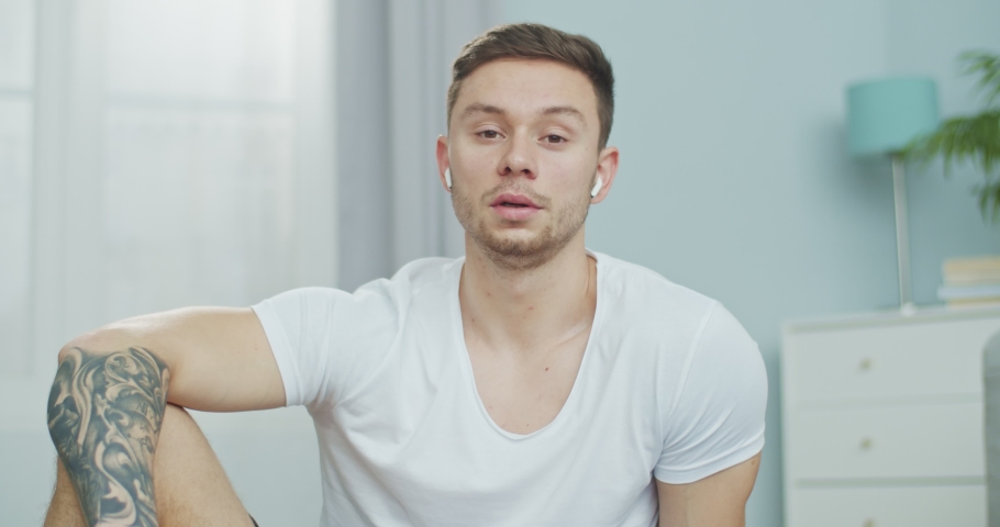 Close up portrait of a young athlete speaking on camera. A sporty guy carying out online fitness training at home. Video lessons on workout, gymnastics, aerobics. Healthy and Wealthy lisfestyle.
