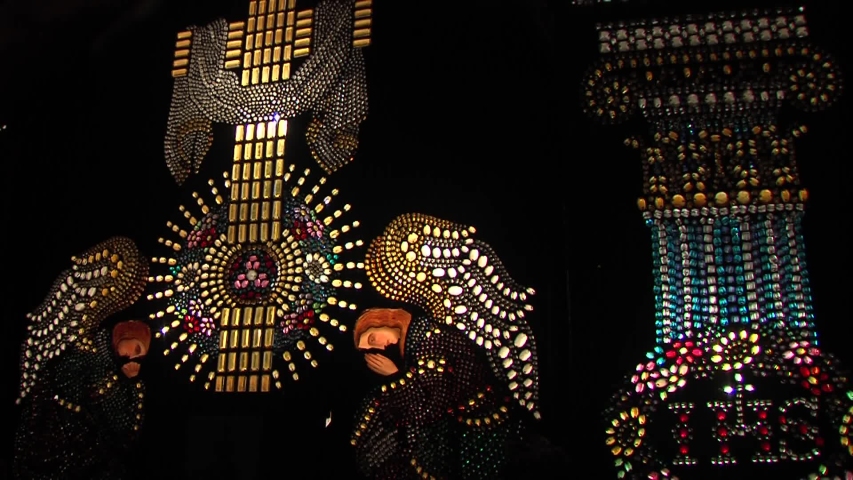 Illuminated mosaic with cross and angels in dark church, left pan