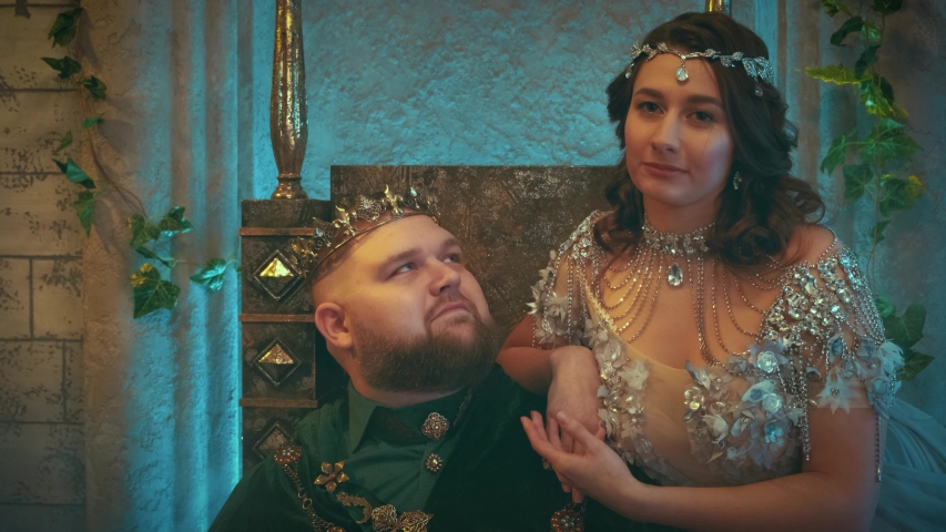 Fantasy portrait young woman medieval queen, stroking king husband, looking with love. royal family sits on throne. Vintage room gothic castle. jewelry crown. Carnival men costume. Art dress clothes
