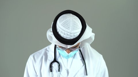 Arabic Doctor wearing Mask And protective gloves Showing Stop Corona Virus Sign With Hand showing stop sign on hospital . Novel coronavirus 2019-nCoV COVID 19 